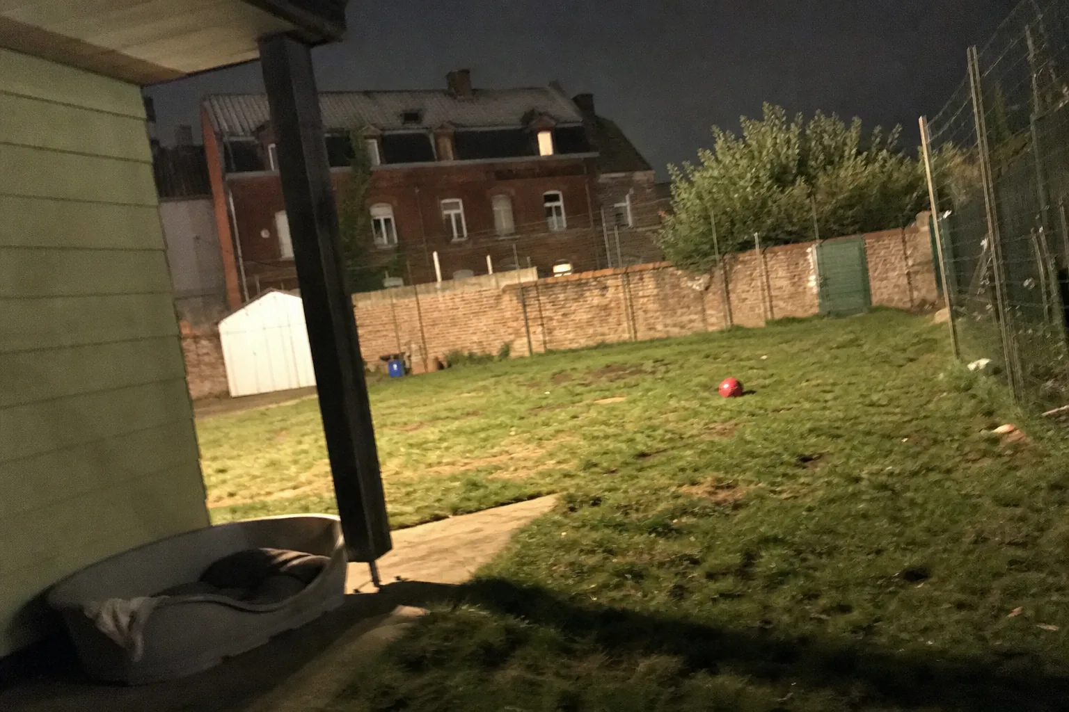 Grand jardin clôturé avec un gros panier pour chien sous un auvent