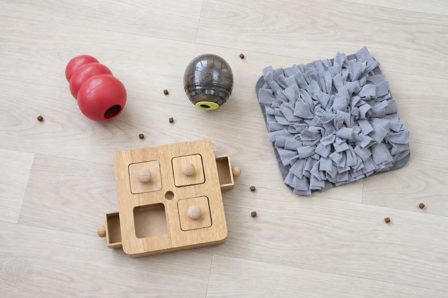 Jouet en caoutchouc à garnir, balle distributrice, puzzle en bois et tapis de fouille posés au sol